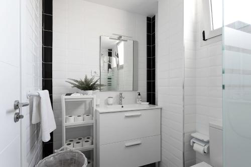 een witte badkamer met een wastafel en een spiegel bij Almar Apartamento en Los Cristianos con AC in Los Cristianos
