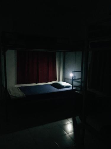 a bed in a dark room with a red curtain at Sea Sands Beach Hostel in Negombo