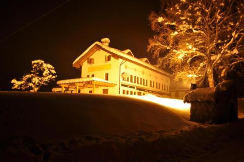 a building is lit up in the snow at night at Rifugio Pranolz in Trichiana