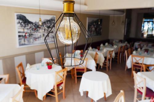 a restaurant with white tables and chairs and a chandelier at Hotel Argegno in Argegno