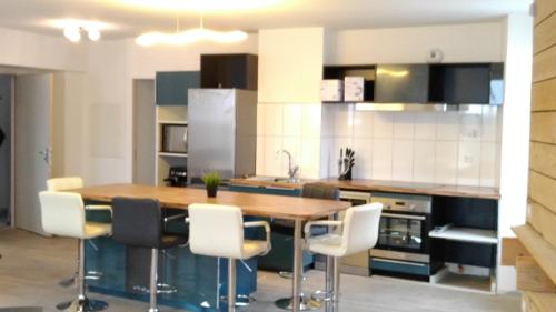 a kitchen with a wooden table and white chairs at magnifique appartement 100m² hyper centre Luz in Luz-Saint-Sauveur