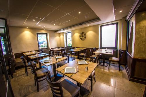 a restaurant with wooden tables and chairs and windows at Hotel Le Pont Neuf in Saint-Affrique