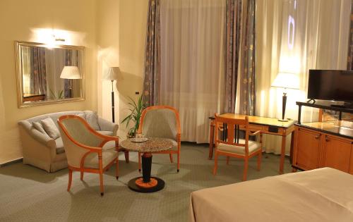 ein Hotelzimmer mit einem Bett, einem Tisch und Stühlen in der Unterkunft Hotel Central in Nagykanizsa