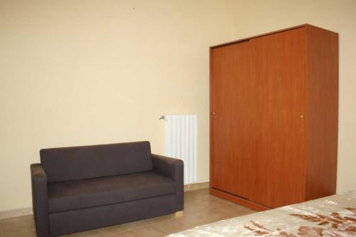 1 dormitorio con silla y armario de madera en Appartamento Vacanze, en San Giovanni Rotondo