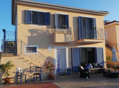a house with blue shuttered windows and a patio at Villa Finiki Messinia upstairs in Foiníki