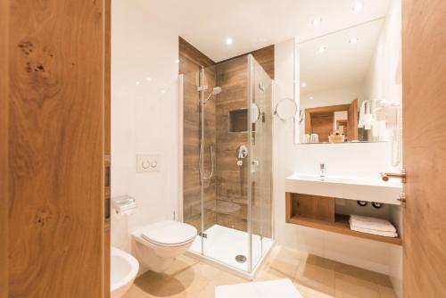 a bathroom with a shower and a toilet and a sink at Hotel Ariadne in Rosenheim