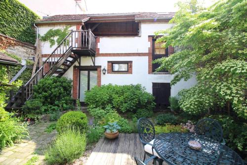 a garden with a table and chairs in front of a house at Jardin de Mathilde in Nangis