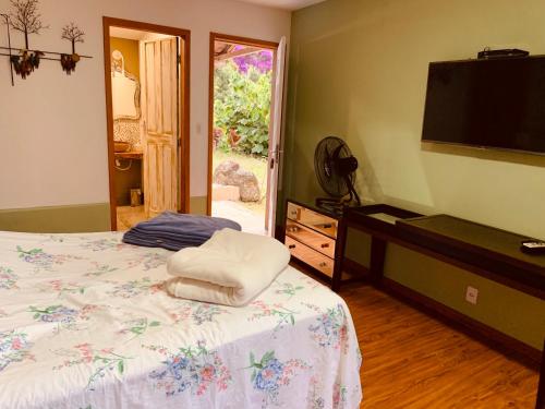 a bedroom with a bed and a flat screen tv at Pousada Quinta das Nascentes in Petrópolis