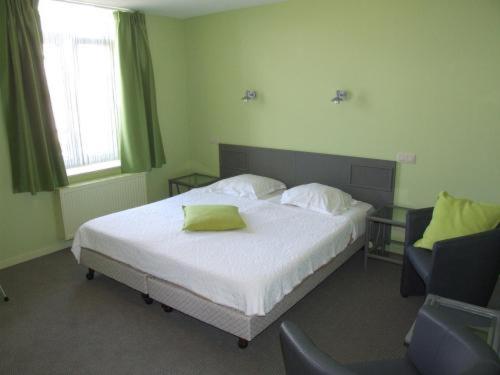 a bedroom with a bed with a green pillow on it at Well'in Hotel in Wellin