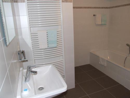 a white bathroom with a sink and a tub at Well'in Hotel in Wellin