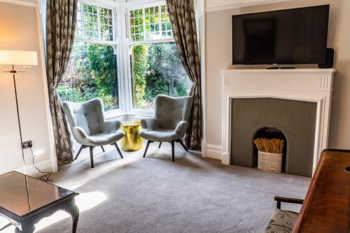 a living room with two chairs and a fireplace at The Firs in Bowness-on-Windermere