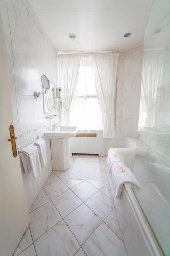a white bathroom with a tub and a sink at Hotel Meurice in Calais