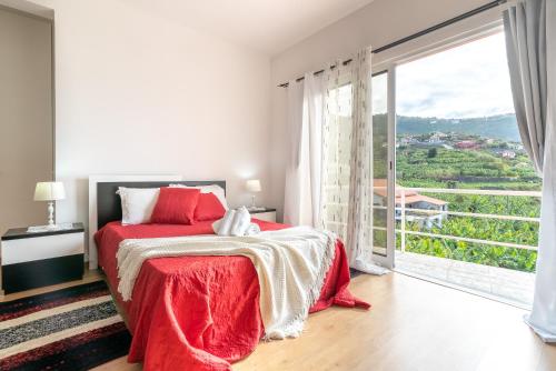 a bedroom with a red bed and a large window at Casa Annie in Arco da Calheta