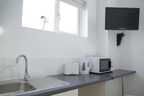 a kitchen counter with a microwave and a sink at TLK Apartments & Hotel - Beckenham in Beckenham