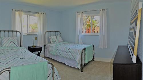 a blue bedroom with two beds and two windows at Private heated pool , resort style home , minutes from the beach in Deerfield Beach