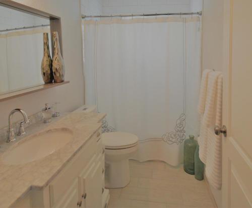 a white bathroom with a toilet and a sink at Private heated pool , resort style home , minutes from the beach in Deerfield Beach