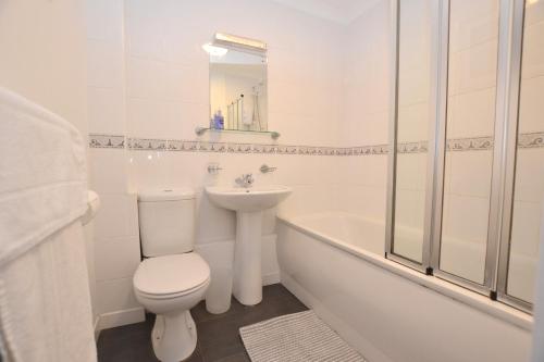 a white bathroom with a toilet and a sink at Beach View Apartments in Porthtowan