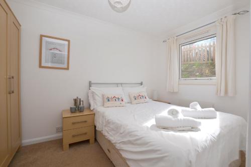 a bedroom with a white bed with towels on it at Beach View Apartments in Porthtowan