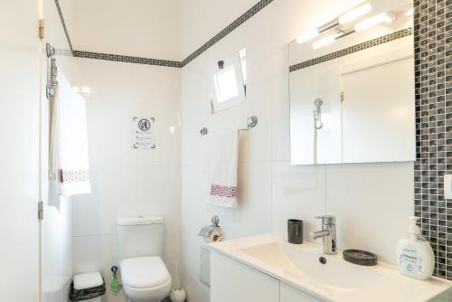 a white bathroom with a toilet and a sink at Casa Annie in Arco da Calheta