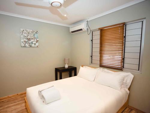 a bedroom with a white bed and a window at Platinum Cawa Apartments in Nadi