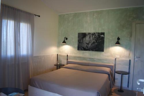 a bedroom with two beds and two lights on the wall at Agriturismo La Facenda in Albinia