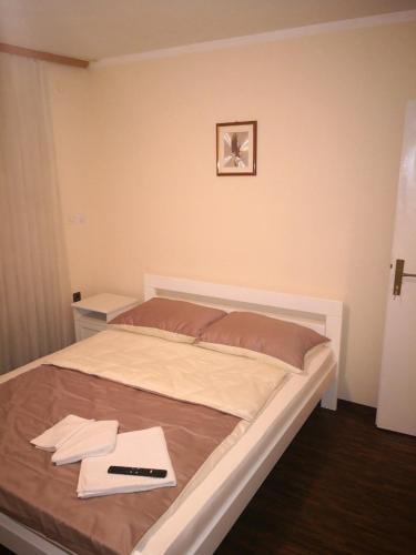 a bedroom with a bed with a remote control on it at Sobe i apartmani Lipa 12 in Repušnica