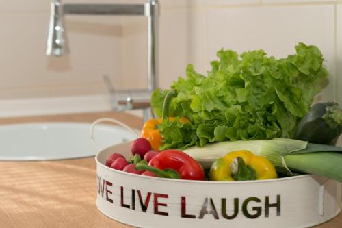 a bowl of vegetables sitting on a counter with the words we live laugh at Apartments Gacka Valley in Otočac