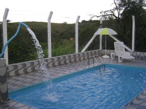una piscina con una fuente y una silla en Pousada dos Tucanos, en São Thomé das Letras