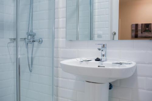 La salle de bains blanche est pourvue d'un lavabo et d'une douche. dans l'établissement Hotel Madrid, à Las Palmas de Gran Canaria