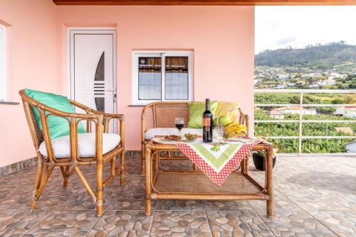 a patio with two chairs and a table with a glass of wine at Apartment Annie 2 in Arco da Calheta