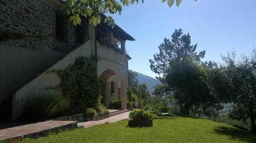 a house with a green yard next to a building at Casale degli ulivi in Gualdo Tadino