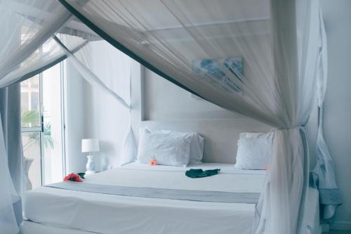 a bedroom with a white bed with a canopy at Paje Beach Apartments & Hotel in Paje