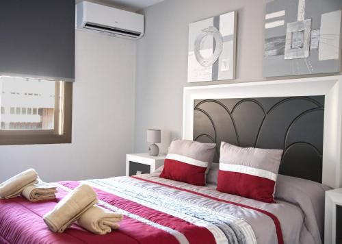 ein Schlafzimmer mit einem großen Bett mit roten und weißen Kissen in der Unterkunft Sur Suites Palmeras 3 in Fuengirola