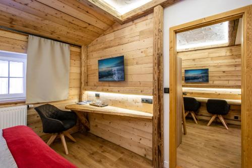 a room in a log cabin with a desk and chairs at Hotel Olympie in Špindlerův Mlýn
