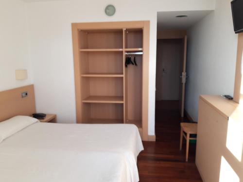 a bedroom with a white bed and a closet at Hotel Puigcerdà in Puigcerdà