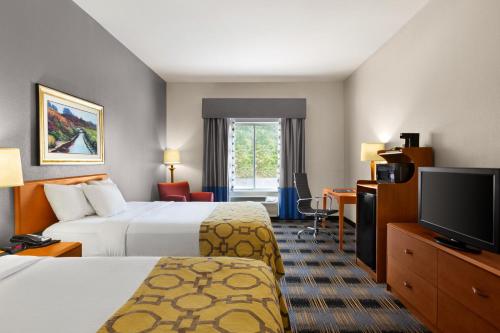 a hotel room with two beds and a flat screen tv at Baymont by Wyndham Lithia Springs Atlanta in Lithia Springs