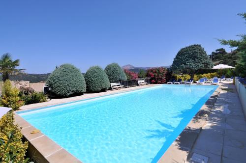 a large swimming pool with chairs and trees at Domaine de Saint Pierre in Cargèse