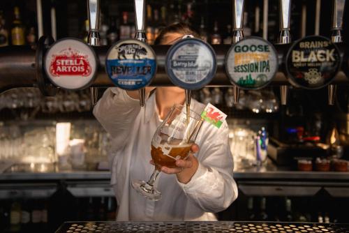 a bartender holding a glass of beer at a bar at Novotel Cardiff Centre in Cardiff