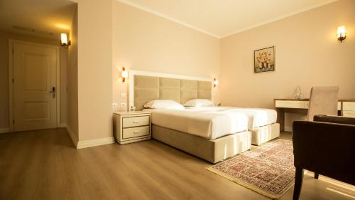 a bedroom with a large white bed and a desk at Royal Hill Hotel in Tirana