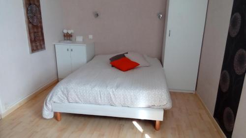 - une petite chambre avec un lit blanc et un oreiller rouge dans l'établissement Chambres des Noels, à Faye-d'Anjou