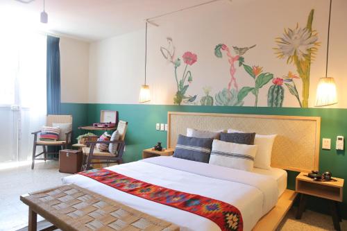 a bedroom with a large bed with a green wall at Selina Oaxaca in Oaxaca City