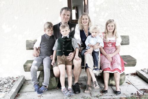 a family sitting on a bench posing for a picture at Hotel Daimerwirt in Moosinning