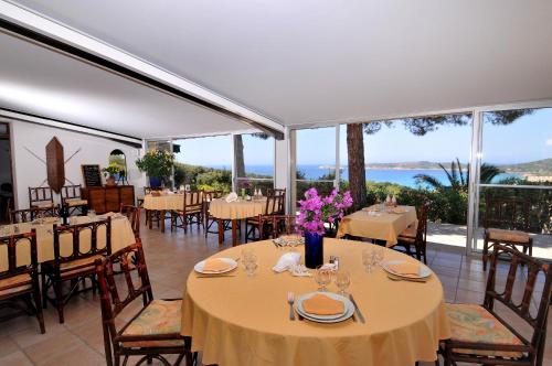 a dining room with tables and chairs and large windows at Domaine de Saint Pierre in Cargèse