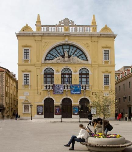 a group of people sitting in front of a yellow building at Aspalathos Residence in Split