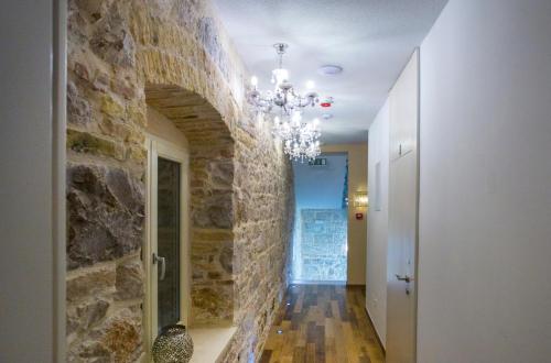 a hallway with a stone wall and a chandelier at Aspalathos Residence in Split