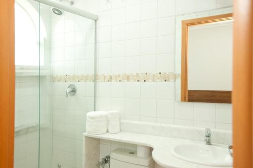 a white bathroom with a sink and a mirror at Hotel Colonial Plaza in Itu