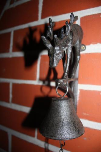 a bronze bell hanging on a brick wall at LA RIVIERE DU BIEN ETRE in Chaumont-Gistoux
