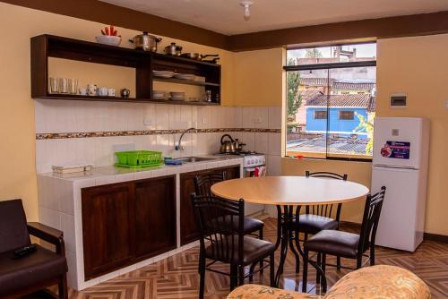 a kitchen with a table and some chairs and a table at Departamentos Santa Ana Barrio Tradicional in Cusco