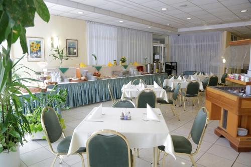 a restaurant with white tables and chairs and a counter at Hotel Bara Gellért in Budapest