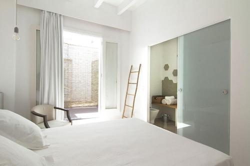 a white bedroom with a bed and a window at Mon hotel in Ciutadella